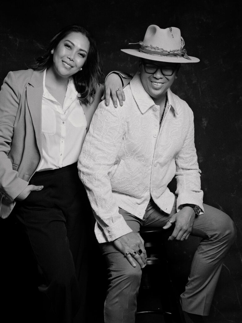 man and woman in black and white photo wearing blazer and fedora hat